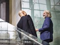 Two corporate executives talking while ascending stairs