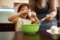 Girl breaking egg while grandma holding whisk