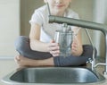 Caucasian little girl drinking from water tap or faucet in kitchen. Pouring fresh drink. Healthy lifestyle. Water quality check Royalty Free Stock Photo