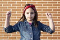 Caucasian little girl flexing her arms with strength isolated on brick wall. Strong woman