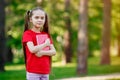 Caucasian Little Girl With Long Hair And With a Book in Against Green Summer Park