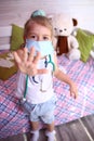 Caucasian little girl in a medical mask at home in her room. Quarantine protection against coronavirus. Home insulat Royalty Free Stock Photo