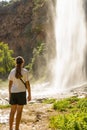 Caucasian little girl in nature, is posing on her back with a waterfall in the background