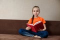 Caucasian Little Girl Sitting On The Sofa Reading a Book At Home Royalty Free Stock Photo