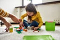 Caucasian little girl spending time with african american baby sitter, playing with construction toys set, sitting on Royalty Free Stock Photo