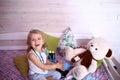 Caucasian little girl with stethoscope at home playing doctor with big blue enema to treat a bear. Little therapist. Coronavirus Royalty Free Stock Photo