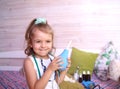 Caucasian little girl with stethoscope at home playing doctor with big blue enema to treat a bear. Little therapist. Coronavirus Royalty Free Stock Photo