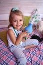 Caucasian little girl with stethoscope at home playing doctor with big blue enema to treat a bear. Little therapist. Coronavirus Royalty Free Stock Photo