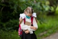Caucasian little girl in a white blouse, with a briefcase. In the hands of a school book. A cute student in a medical mask. Royalty Free Stock Photo