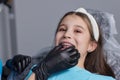 caucasian little kid girl invisible aligner and pointing to her perfect straight teeth. Dental healthcare and confidence