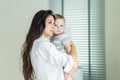 Caucasian loving mom carry cute baby boy child on hand in living room. Happy family, attractive caring young mother holding