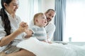 Caucasian loving parents play with baby boy child on bed in bedroom. Happy family, attractive beautiful young couple dad and mom Royalty Free Stock Photo