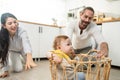 Caucasian loving parents play with baby toddler in kitchen on floor. Beautiful couple mother and father play with young little son Royalty Free Stock Photo