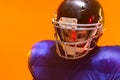 Caucasian male american football player wearing helmet with neon orange lighting