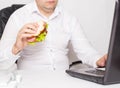 Caucasian male fat office worker is having a sandwich in the office. The concept of malnutrition and obesity in the