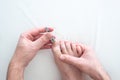 Caucasian male hand and foot cutting his toenails with a metal nail clipper on a white surface top view close up shot Royalty Free Stock Photo