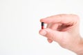 Caucasian male hand holding a medical black and red capsule pill between fingers. Close up studio shot, isolated on white Royalty Free Stock Photo