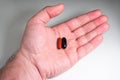 Caucasian male hand holding a red and black medical capsule pills isolated on white top view Royalty Free Stock Photo