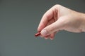 Caucasian male hand holding a red medicine capsule pill between fingers close up shot isolated studio shot Royalty Free Stock Photo