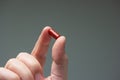 Caucasian male hand holding a red medicine capsule pill between fingers close up shot isolated studio shot Royalty Free Stock Photo