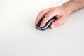 Caucasian male hand holding and using a small black wireless computer mouse  on white background. Close up studio shot Royalty Free Stock Photo