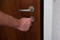 Caucasian male hand unlocking apartment brown wooden door from inside close up shot Royalty Free Stock Photo