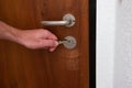 Caucasian male hand unlocking apartment brown wooden door from inside close up shot