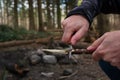 Caucasian male hand in winter jacket sharpening a wooden stick skewer with a nondescript pocket knife close up shot unrecognizable Royalty Free Stock Photo