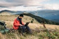 Caucasian male hiker working with laptop sitting on the mountain against the backdrop of beautiful scenic rocks. Royalty Free Stock Photo