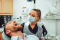 Caucasian male patient sitting in chair while have teeth cleaned by female oral hygienist