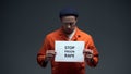 Caucasian male prisoner holding stop prison rape sign in cell, sexual harassment