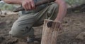 Caucasian male survivalist using branch and machete to cleave firewood at camp in wilderness