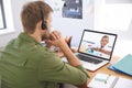 Caucasian male teacher using computer and phone headset on video call with schoolboy