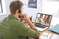 Caucasian male teacher using laptop and phone headset on video call with school children learning fr Royalty Free Stock Photo