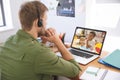 Caucasian male teacher using laptop and phone headset on video call with schoolboy learning from hom Royalty Free Stock Photo