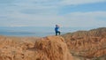 A Caucasian male traveler in a blue T-shirt stands on the top of a mountain and drinks water from a purple bottle Royalty Free Stock Photo