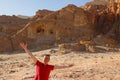 Caucasian male traveler in a red T-shirt joyfully spread his hand against a sandy rock in Timna National Park, Israe Royalty Free Stock Photo