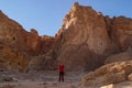 Caucasian male traveler in a red T-shirt posing against the backdrop of a sandy rock in the Timna National Park, Israel