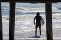 A caucasian male in a wetsuit holding a surfboard is seen standing by at the shoreline before entering the rough ocean Royalty Free Stock Photo