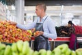 Merchandiser setting out plums in greengrocery