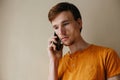 Caucasian man with beard in casual orange shirt talking with mobile phone in living room about serious problem Royalty Free Stock Photo