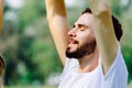 Caucasian man with beard eyes closing and feeling with the fresh air in public park