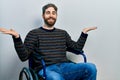 Caucasian man with beard sitting on wheelchair celebrating victory with happy smile and winner expression with raised hands