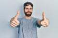 Caucasian man with beard wearing casual grey t shirt approving doing positive gesture with hand, thumbs up smiling and happy for Royalty Free Stock Photo
