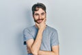 Caucasian man with beard wearing casual grey t shirt looking confident at the camera smiling with crossed arms and hand raised on Royalty Free Stock Photo