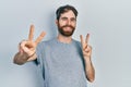 Caucasian man with beard wearing casual grey t shirt smiling looking to the camera showing fingers doing victory sign Royalty Free Stock Photo