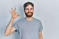 Caucasian man with beard wearing casual grey t shirt smiling positive doing ok sign with hand and fingers Royalty Free Stock Photo