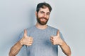 Caucasian man with beard wearing casual grey t shirt success sign doing positive gesture with hand, thumbs up smiling and happy Royalty Free Stock Photo