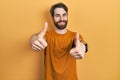 Caucasian man with beard wearing casual yellow t shirt approving doing positive gesture with hand, thumbs up smiling and happy for Royalty Free Stock Photo