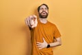 Caucasian man with beard wearing casual yellow t shirt laughing at you, pointing finger to the camera with hand over body, shame Royalty Free Stock Photo